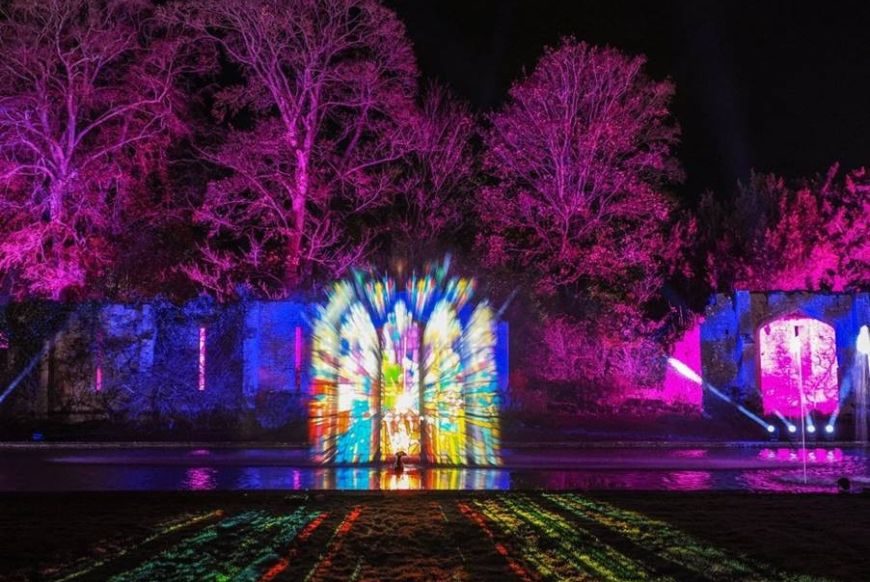 Visual light show projected onto the water fountains and long pond in front of the Tithe Barn at Sudeley Castle, Gloucestershire